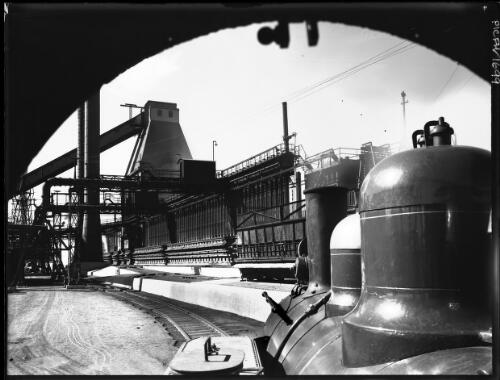[The coke ovens, BHP Steelworks, Newcastle, railway tracks and industrial plant viewed through an archway] [picture] : [Newcastle, New South Wales] / [Frank Hurley]