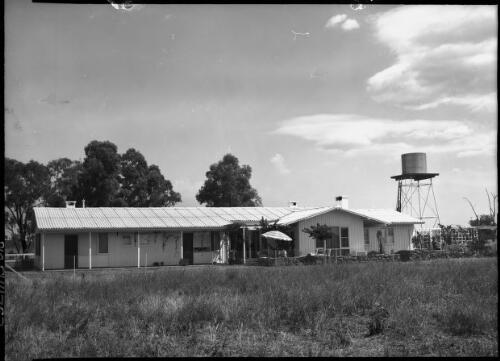 [Homestead on a property, with a water tank on a very high tank stand and an umbrella] [picture] / [Frank Hurley]