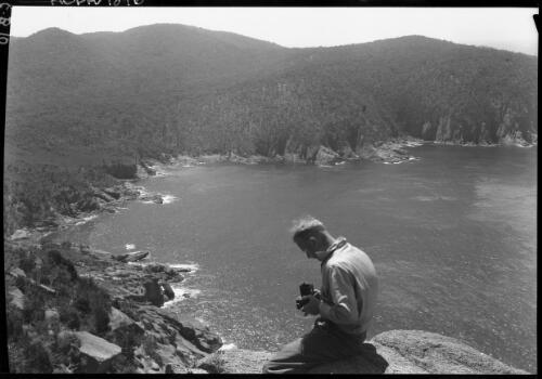 Sleepy Bay from 'Baldy', figure with camera in FG [picture] : [Coles Bay, Tasmania] / [Frank Hurley]