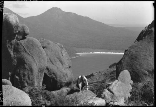 Wineglass Bay from Baldy, figure in FG [rocks and water] [picture] : [Coles Bay, Tasmania] / [Frank Hurley]