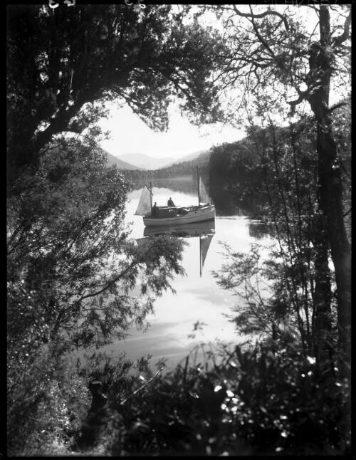 Scene through trees, boat in centre [picture] : [Gordon River, Tasmania] / [Frank Hurley]