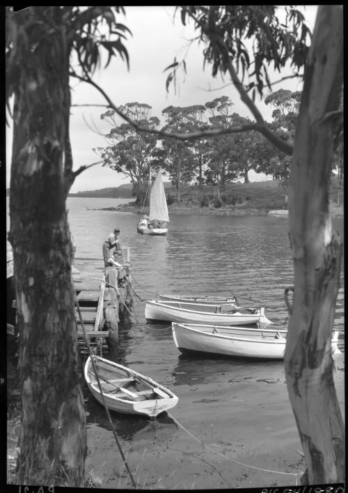 Port Arthur Landing [with boats and figures, framed by trees] [picture] : [Port Arthur, Tasmania] / [Frank Hurley]