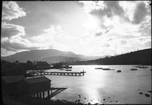 Sunset looking toward Mt Wellington from Bellerive [jetty with boats and Mobil Oil sign] [picture] : [Hobart, Tasmania] / [Frank Hurley]