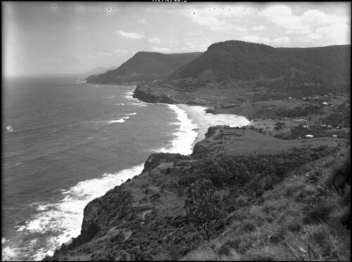 [Stanwell Park from Bald Hill looking south, coastal scene with farm buildings, headlands, beach, and road] [picture] : [South Coast, New South Wales] / [Frank Hurley]