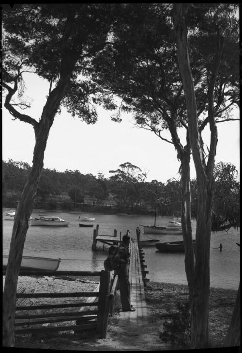 St Helen's Bay [with jetty and figure with backpack] [picture] : [East Coast, Tasmania] / [Frank Hurley]