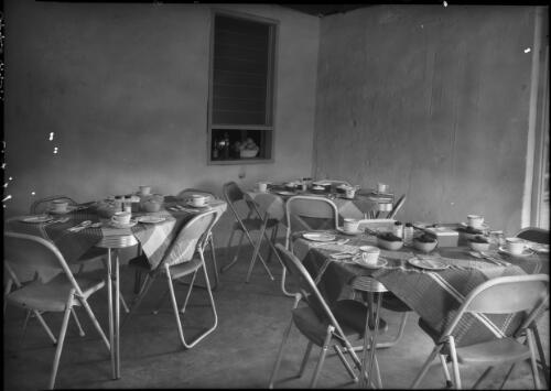 Accommodation Glen Helen [interior shot showing a dining room, with three tables set with tablecloths, cutlery and china] [picture] : [Central Australia] / [Frank Hurley]