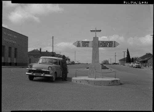 [Country town with road sign, closest town Thevenard 2 miles and building The Savings Bank of South Australia] [picture] : [South Australia] / [Frank Hurley]