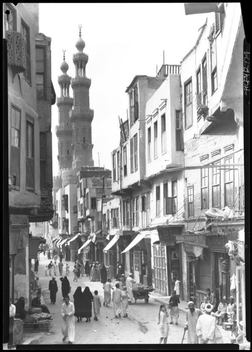 Street in old Cairo near the Bab Mitwelly [Bab El Mitwelly, with two minarets, food stalls, figures] [picture] : [Cairo, Egypt, World War II] / [Frank Hurley]