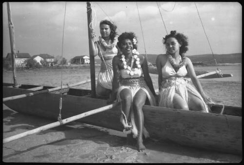 [Three women wearing leis and grass skirts in a canoe] [picture] / [Frank Hurley]