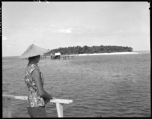 [Unidentified woman wearing hat, with small island and jetty in background] [picture] / [Frank Hurley]