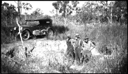 Typical of the country round Burrumdie, 1925 [three figures and motor vehicle] [picture] : [Central Australia] / [Frank Hurley]