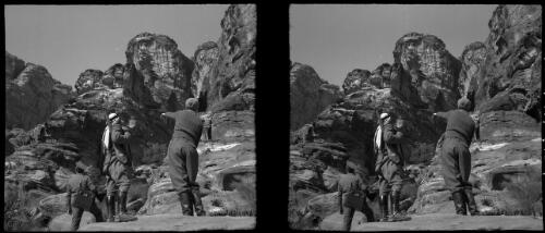 [Three men ascend a gorge, all wearing military uniform, with the central figure wearing Arab headdress and carrying a rifle, Petra] [picture] : [Jordan, World War II] / [Frank Hurley]