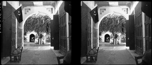 Scenes Derna Harbour and market [shot from interior through archway showing tailors, cobblers behind in small shopfronts] [picture] : [Libya, World War II] / [Frank Hurley]