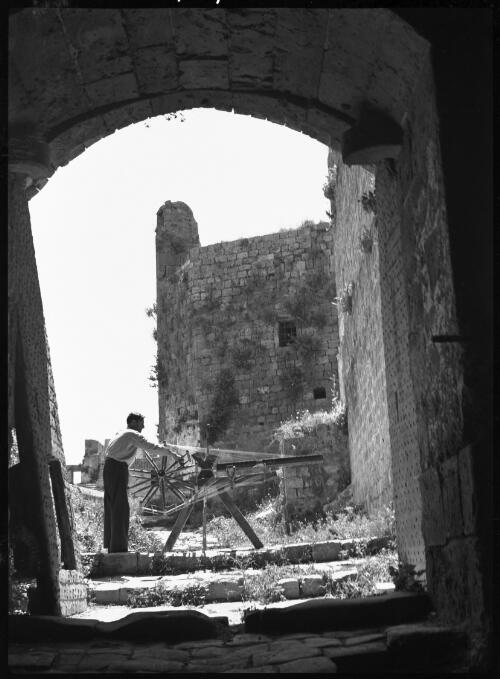 This weaver has chosen the entrance to the Crusaders stronghold at Tripoli for his workroom, a pleasant cool spot in the heat of summer [picture] : [Lebanon, World War II] / [Frank Hurley]