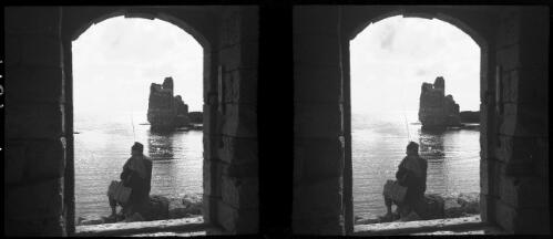 Ruins of Byblos Jbeil [view through a doorway, a man fishing] [picture] : [Lebanon, World War II] / [Frank Hurley]