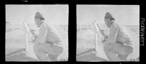 British War Cemetery El Alamein [figure painting on cross-shaped headstone] [picture] : [Egypt, World War II] / [Frank Hurley]