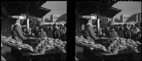 Jerusalem [market scene, a woman behind a stall of bread] [picture] / [Frank Hurley]