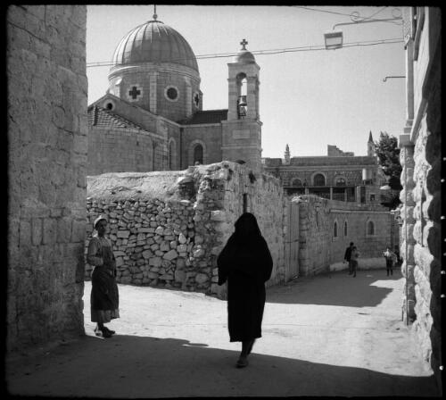 Byways & alleys in Jerusalem including St Stephens Gate & Jaffa Gate [walking past a domed building, Palestine] [picture] / [Frank Hurley]
