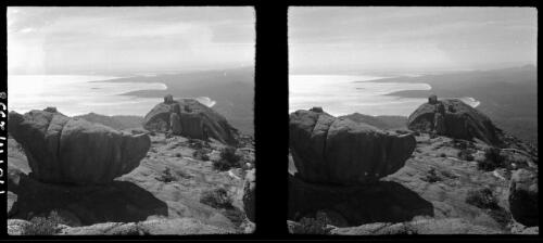 [View down to large body of water with land mass to the right ca. 1938-1947, large rocks in foreground] [picture] : [Tasmania] / [Frank Hurley]