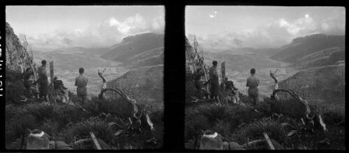 [Group of four figures looking down into a valley from the side of a mountain, with distant small lake or river, ca. 1938-1947] [picture] : [Tasmania] / [Frank Hurley]