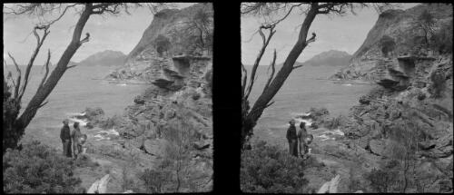 [Two figures by water's edge, rocky shore, expanse of water, distant landforms ca. 1938-1947] [picture] : [Tasmania] / [Frank Hurley]