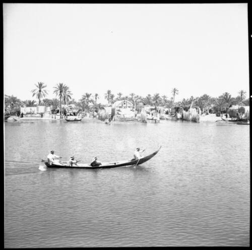 Chubaish and vicinity, sundry shots [a canoe with four figures on a river with a town in the background, 1944] [picture] : [Iraq, World War II] / [Frank Hurley]