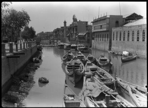 [Canoes in a canal with buildings on one side, including a minaret, 1944] [picture] : [Iraq, World War II] / [Frank Hurley]