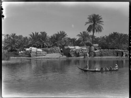[Canoe with figures on river, stacks of reeds, 1944] [picture] : [Iraq, World War II] / [Frank Hurley]