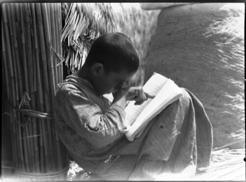 Reading Arabic at school in Chubaish to a group of children weaving mats [1944, 2] [picture] : [Iraq, World War II] / [Frank Hurley]