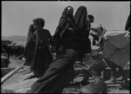 [Group of robed figures, man pouring water from a metal container into a bowl held by a kneeling figure] [picture] : [Egypt, World War II] / [Frank Hurley]