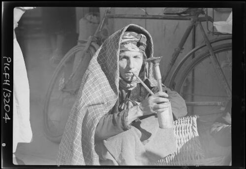 Yemenite woman smoke homemade hubble-bubble pipe, Jerusalem [picture] : [Portrait Studies, Libya, World War II] / [Frank Hurley]