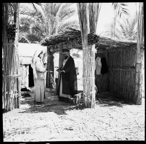 [Two figures standing in a house made of reeds, Chubaish?] [picture] : [Portrait Studies, Libya, World War II] / [Frank Hurley]