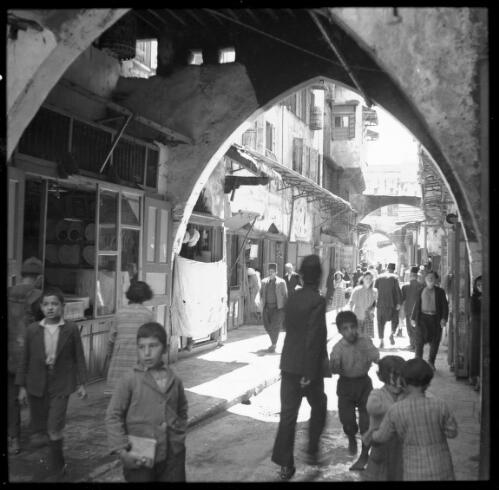 [Domed archway with figures, opening onto a busy narrow street] [picture] : [Portrait Studies, Libya, World War II] / [Frank Hurley]