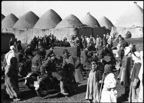 Typical mud-domed village Northern Syria [scene of villagers and motorcycle-mounted AIF soldiers] [picture] / [Frank Hurley]