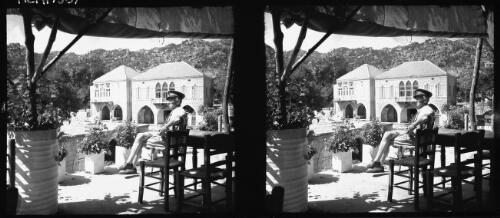 Self at Akhouf [uniformed Captain Hurley seated on verandah overlooking town] [picture] / [Frank Hurley]