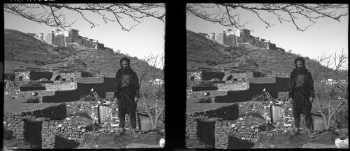 The Crac-de-Chevalier, one of the finest preserved of the Crusader fortresses in N. Syria [figure in front of buildings below the Castle] [picture] / [Frank Hurley]