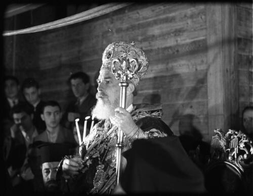 Greek Service in Holy Sepulchre [Greek Orthodox priest in profile with crown, staff and robes] [picture] / [Frank Hurley]