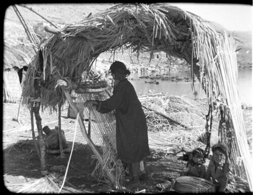 Huleh [Palestine, woman at her hand-made loom weaving reed mats] [picture] / [Frank Hurley]