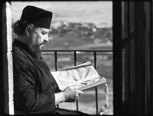 Mount Quarantina Jericho [priest reading on verandah of Greek Orthodox monastery at Mount Quarantina (Mount of Forty)] [picture] / [Frank Hurley]