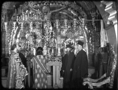 Opening shots in Church of Holy Sepulchre [Greek priests at the altar in front of the site of Jesus' crucifixion, the 12th station of the Cross, Church of the Holy Sepulchre] [picture] / [Frank Hurley]