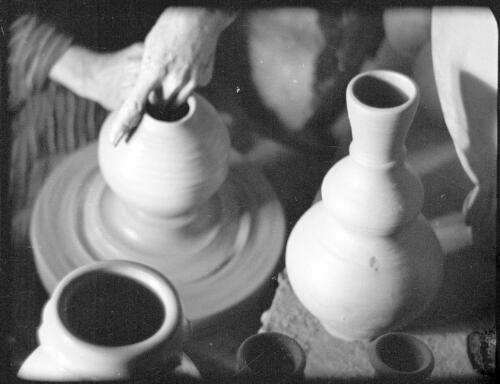 Making clay pottery & Alskelon ruins [hands turning pots on a pottery wheel] [picture] / [Frank Hurley]