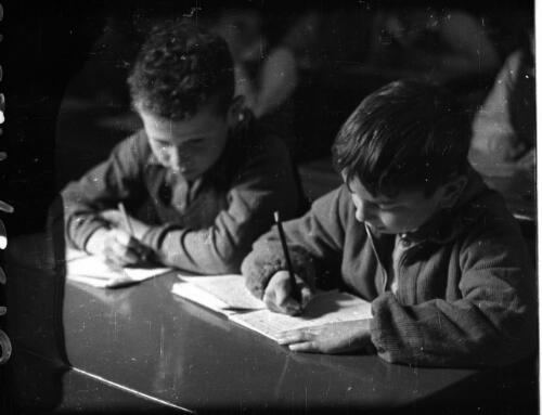 Athlit & Jewish village showing farmwork & school [two schoolchildren writing at their desks] [picture] / [Frank Hurley]