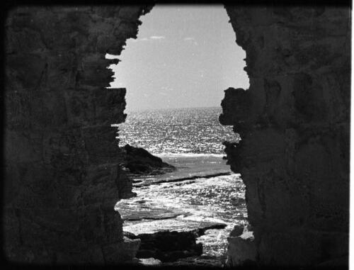 Athlit & Jewish village showing farmwork & school [sea scene framed by arch of ruins] [picture] / [Frank Hurley]