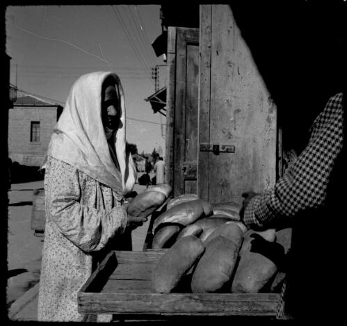 [Lady buying bread from a street stall] [picture] / [Frank Hurley]