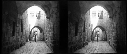 Sundry stereos, Jerusalem [view down narrow cobbled street with young child and boy carrying basket, Old City] [picture] / [Frank Hurley]