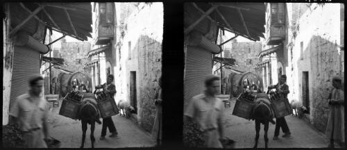 Sundry stereos, Jerusalem [man with donkey laden with drink boxes in narrow street, Old City] [picture] / [Frank Hurley]