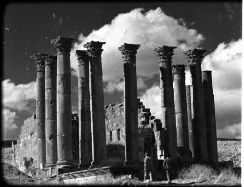 Jerash [two men standing in front of a ruined building with a group of Corinthian columns in front, 1] [picture] : [Jordan] / [Frank Hurley]
