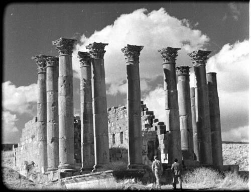 Jerash [two men standing in front of a ruined building with a group of Corinthian columns in front, 2] [picture] : [Jordan] / [Frank Hurley]