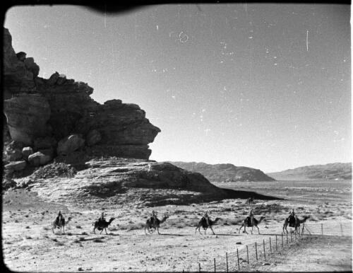 Camels, camel detachment [mounted troops in single file, in profile, long shot, 1] [picture] : [Jordan] / [Frank Hurley]