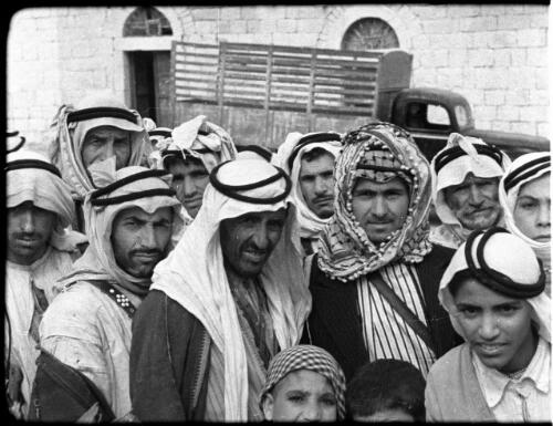 Arab Legion [group of men and boys in Arab dress foreground, truck and building behind] [picture] : [Jordan] / [Frank Hurley]